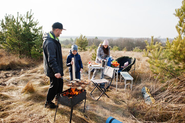 Family barbecuing on a deck in the pine forest. Bbq day with grill.