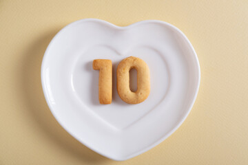 Biscuits forming number 10 on the white plate and yellow light background