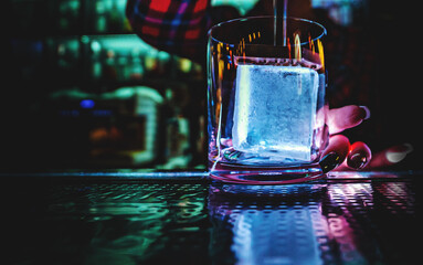woman bartender stamping ice cube in the glass on the bar counter