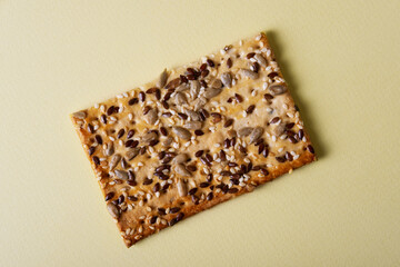 Cereal bread with flax and sunflower seeds on a light yellow background