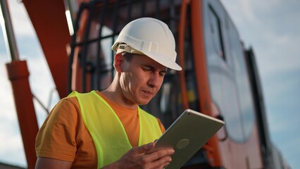 worker in hard a hat with digital tablet near excavator. construction site driver with online digital business tablet. industry construction concept. worker hard hat near excavator truck in uniform.
