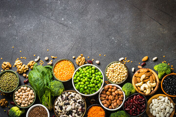 Vegan protein source. Legumes, beans, nuts, vegetables and seeds. Top view on black stone table. Healthy vegetarian food.
