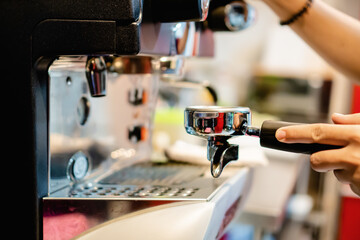 waitress using the filter holder of an industrial coffee machine in a bar or restaurant