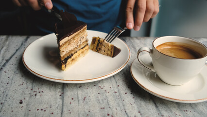 a man in a cafe drinks coffee and cuts a piece of coffee cake
