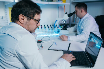 Portrait of a scientist working in the lab examines a test tube with liquid.