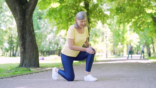 Senior runner with muscle pain. Mature old woman massaging, trauma injury while jogging outdoors. Fitness female sprain severe stretch pull. Leg muscle cramp calf sport jog injured her leg knee