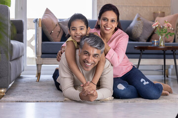 Portrait of cheerful parents with daughter lying down on carpet in the living room