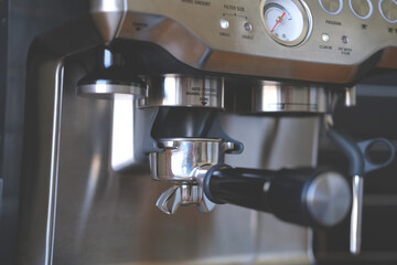 Empty portafilter (filter holder) in a coffee machine before grinding beans, making espresso in coffee maker