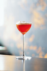 A beautiful full glass with a cocktail on the counter . Red