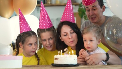 birthday. happy family on holiday party. parents and kids with baby getting ready to blow out fun birthday cake with candles. happy family at birthday. baby blows out the candles on the cake