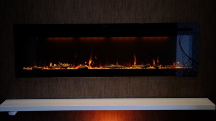 view on electric fireplace with artificial sparkling flame, decor for the interior, orange flame on crystals - obrazy, fototapety, plakaty