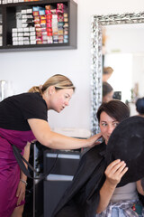 The woman examines her haircut in the mirror at the hairdresser.