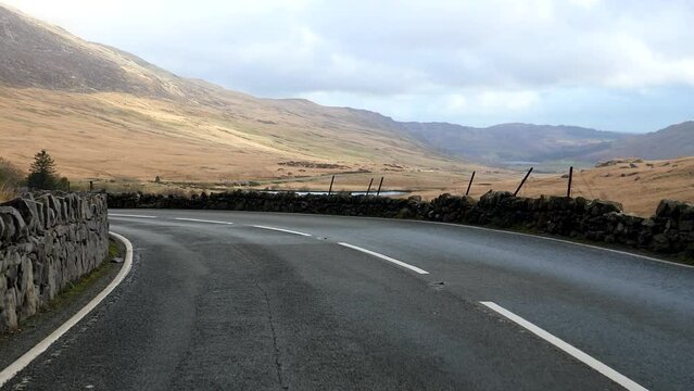 Car front window view driving A4086 road in a beautiful autumn landscape of Snowdonia National Park in North Wales, approaching A498 road junction near Capel Curig.