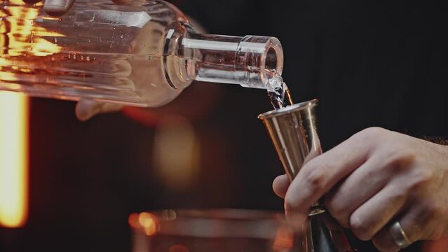 Bartender measure out clear liquid for cocktail with jigger