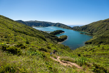 Beautiful landscape of Lake of Fire - " Lagoa do Fogo " in a sunny morning day with blue sky with a couple going down by the small path. São Miguel Island, Azores. 