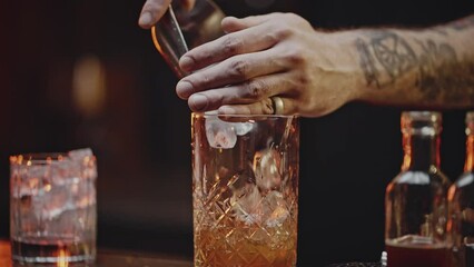 Professional bartender pours ice cubes into finished drink