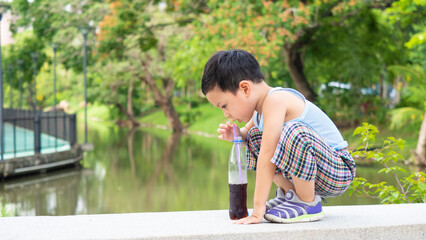 An asian boy drinking soft drink soda on bottle - 508625405