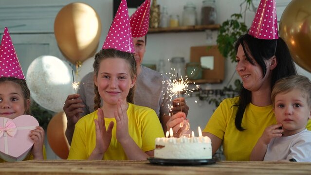 birthday. happy family on holiday party. parents and childs with baby getting ready to blow out fun birthday cake with candles. happy family at birthday. baby blows out the candles on the cake