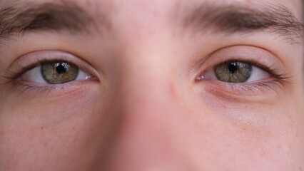 Close up of Man's face. Attractive boy his beautiful green eyes. European young male model looking at camera.extreme