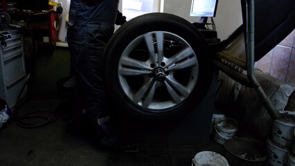 Balancing car wheel on profissional machine equipment by professional mechanic at servise station