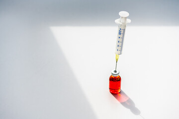 Close-up Medizinische Spritze mit Nadel in einer Ampulle. Darin rote Flüssigkeit, Medikament,...