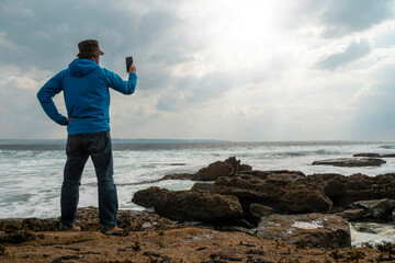 Male tourist standing on a rough stone coast. Aran island, county Galway, Ireland. Blue cloudy sky...