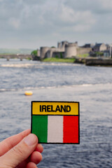 Badge with National flag and sign Ireland in focus. River Shannon and King John castle out of focus...