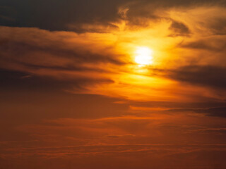 A blurry dramatic celestial sunset with clouds that the sun paints orange. Soft focus, motion is blurry. Beautiful natural background of the sunset sky