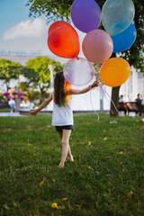cute little caucasian girl with colourful dyed hair walking barefoot with baloons