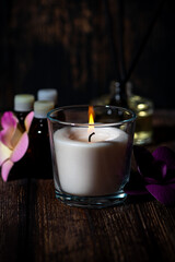 Obraz na płótnie Canvas burning aroma candle on a dark background, spa attributes, vertical