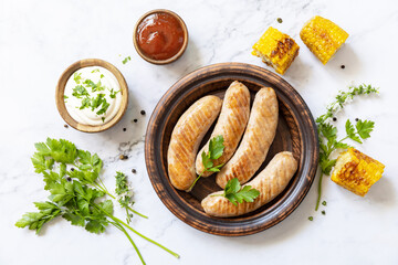 Grill food menu. Summer Party Food. Grilled Sausages with fresh herbs and spices on marble tabletop. View from above.