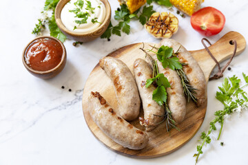 Grill food menu. Summer Party Food. Grilled Sausages with fresh herbs and spices on marble tabletop.