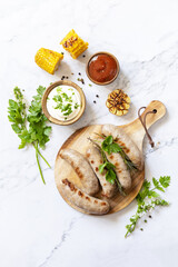 Grill food menu. Summer Party Food. Grilled Sausages with fresh herbs and spices on marble tabletop. View from above.
