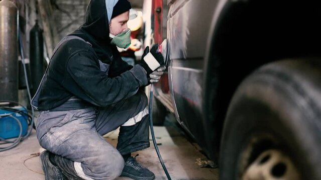 man restores a car body, polishing putty before painting a cargo van. Car body repair.
