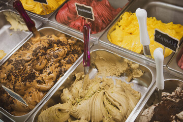 Delicious ice cream sorbet of different flavors in lots in cafe, shop. Tasty Italian refreshing dessert gelato on display. Selective focus top view. Row of typical ice creams background. Summer sweets