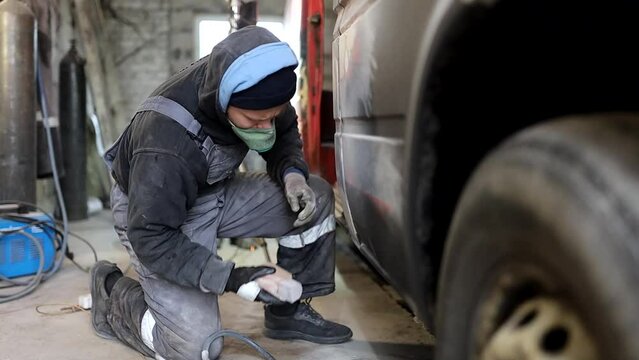 man restores a car body, polishing putty before painting a cargo van. Car body repair.