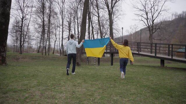 The girl and the boy are holding and walking with the Ukrainian flag. Symbol of empathy. The inscription on the girl's sweater: "Your opinion is important"