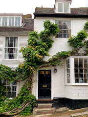 Fototapeta na wymiar Mermaid street view. Old cozy medieval tudor half-timbered house cottage. Summer in Rye. East Sussex, England. Charming town. Architecture, cozy popular touristic destination.covered climbing wisteria