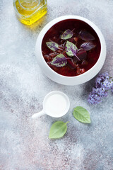 White bowl with red beetroot soup or borsch on a roseate stone background, vertical shot with space, above view