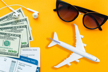Preparation for Traveling concept, airplane, money, passport on yellow background with copy space.