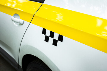 The side of the taxi with a yellow stripe and a checkerboard element