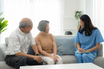 Elderly man and woman sitting on the sofa and talking with nurse at home. Attractive caregiver explain how to take care health. Asian senior with assisted living medication monitoring concept