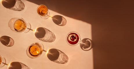 Banner of Summer cocktails with fruit in the sunlight. Fresh juicy beverages in glasses with shadows making trendy pattern on beige background. Delicious lemonade, cold tea, soda and water 