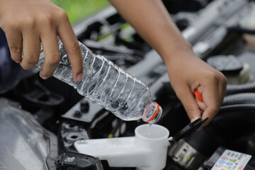 mechanic fill fresh water into windscreen or in water tank wiper on car engine room.