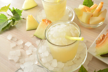 Glasses with iced melon drink and cut fruit around