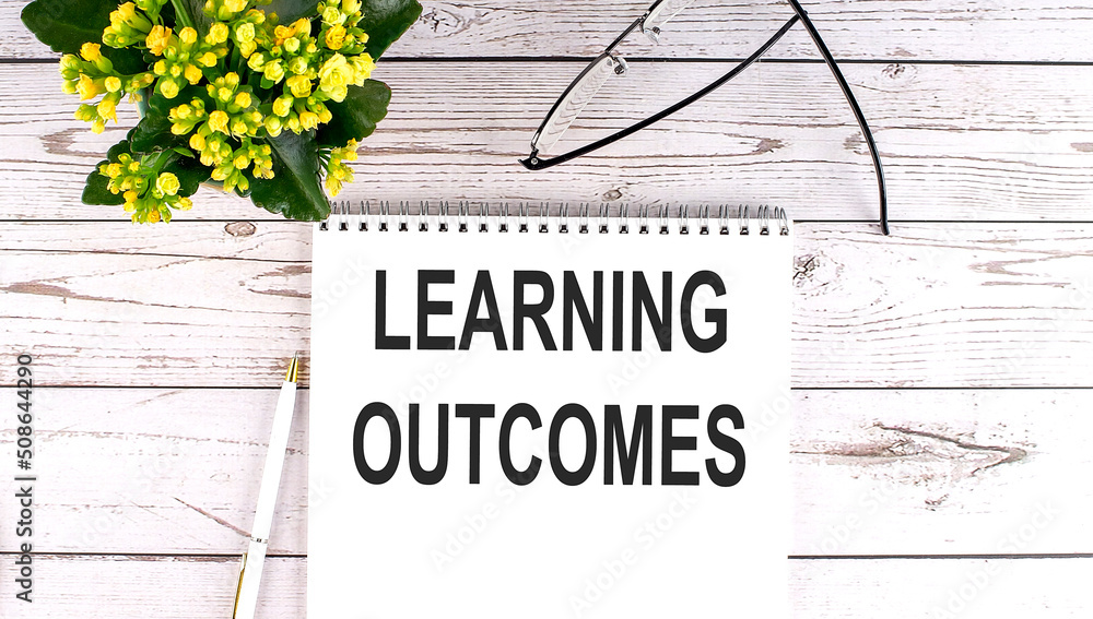 Aufkleber learning outcomes text concept write on notebook on wooden background