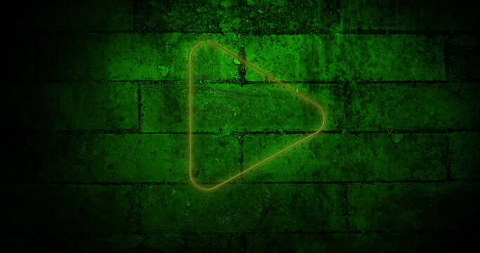 Image of glowing neon play button icon on brick wall