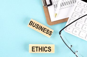 BUSINESS ETHICS text written on wooden block with clipboard ,eye glasses and calculator Business...
