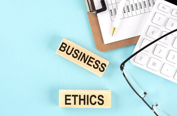 BUSINESS ETHICS text written on wooden block with clipboard ,eye glasses and calculator Business concept.