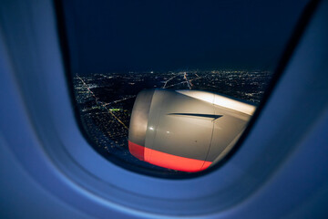 View from window of airplane during take off against illuminated city at night..